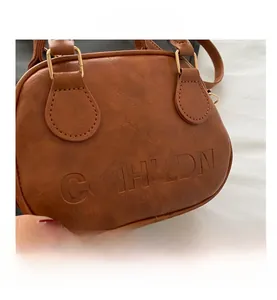 Detail of vintage brown textured leather handbag with gold metal ring and embossed logo