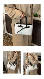 Detail view of a black and white patchwork handbag with gold hardware and strap