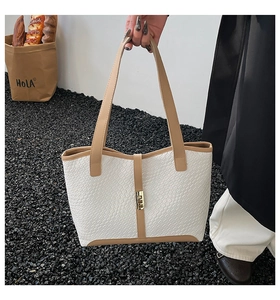 Close-up of white woven leather tote bag with brown straps and golden buckle detail