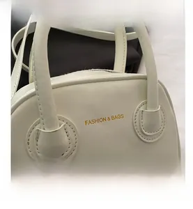 Vue détaillée d'un sac à main blanc minimaliste avec logo doré et poignées solides