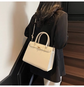 Detail of a creamy beige leather tote bag with metal turn-lock closure on stairs