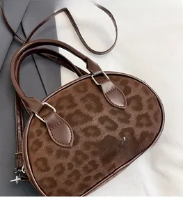 Close-up of retro leopard print suede texture and leather strap on round boston bag