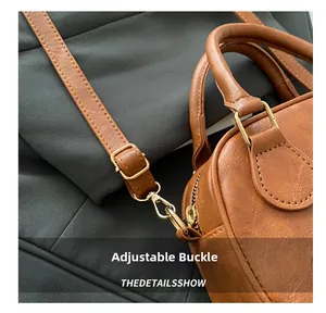 Detailed macro view of the brown leather shoulder bag with adjustable gold buckle hardware
