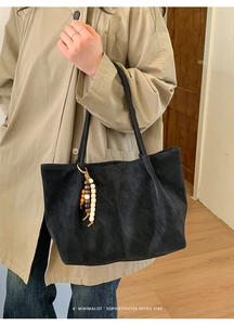 Dettaglio della borsa tote in pelle scamosciata nera con nappa di perline e tracolla