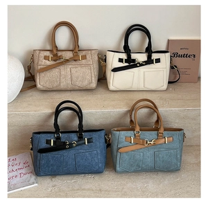 Detail view of four textured retro handbags with gold buckles on a stone step display