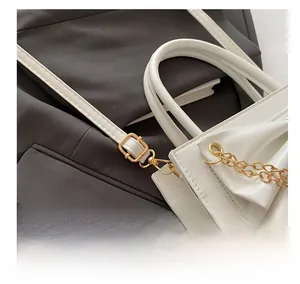 Détail de la boucle de sangle réglable sur sac à main blanc avec chaîne dorée