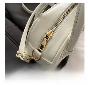 Détail de la fermeture éclair dorée fluide sur un sac bandoulière en similicuir blanc