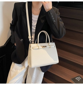 Close-up of white lychee pattern leather handbag with gold metal twist lock and buckle