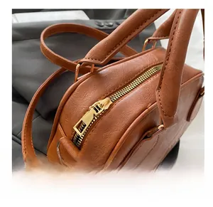 Close-up of vintage brown lychee grain leather bowling bag with gold zipper and embossed texture