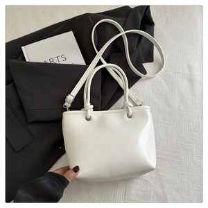 Detailansicht der weißen PU-Leder Eimertasche mit Zylindergriffen und Metallösen