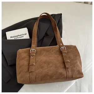 Détail d'un sac à bandoulière en daim marron foncé avec œillets et boucles en argent
