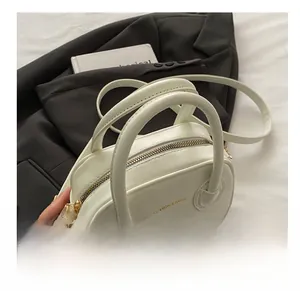 Détail du mini sac à main en cuir blanc avec finitions dorées et texte de mode gaufré