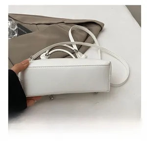 Détail du bas d'un sac blanc avec clous en métal résistant et surpiqûres de précision