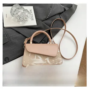 Détail du sac à main trapèze beige avec inscription dorée et motifs de lettres élégants