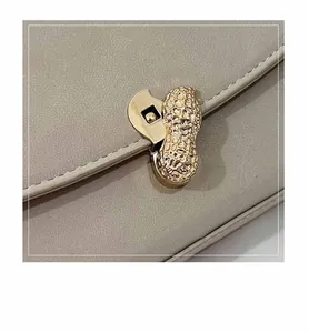 Detail of the golden peanut-shaped metal lock on the lychee textured leather shoulder bag