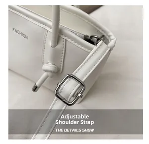 Détail de la bandoulière réglable avec boucle argentée sur un sac cabas blanc