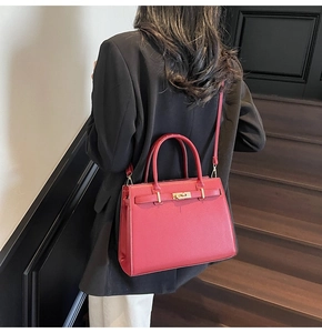 Detail of red bridal handbag with gold twist lock worn by a model in black blazer