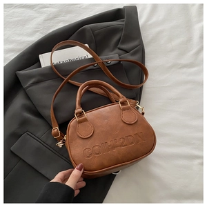 Detailed macro view of vintage brown leather texture and embossed logo on top handle bag