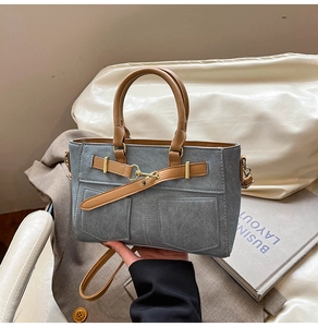 Detail of denim patchwork tote with brown leather handles and decorative pockets