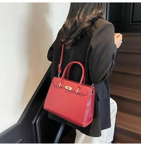 Close-up of red luxury textured tote with golden metal lock and adjustable shoulder strap