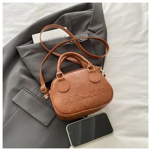 Detail of caramel brown saddle bag with COIH2DN embossed logo on vintage PU leather