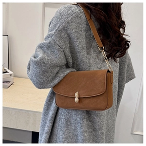Detail of vintage brown shoulder bag with a unique golden peanut-shaped clasp and chain strap