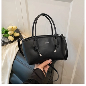 Gros plan du sac à bandoulière noir avec poignée ronde nouée et lettrage Fashion détaillé