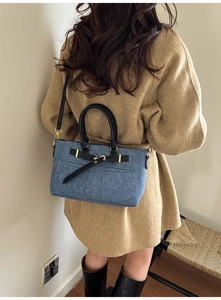 Detail of navy textured handbag featuring leather straps and gold metal hardware