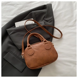 Top view of brown Boston bag with litchi texture on a grey suit and white cloth