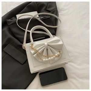 Détail d'un sac à main blanc en PU avec grand nœud et chaîne de perles