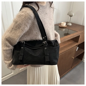 Détail d'un sac à bandoulière en cuir noir avec boucles argentées et sangles à œillets