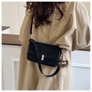 Detail of black matte shoulder bag with gold peanut buckle and plush monster charm