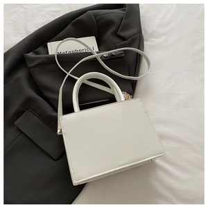 Vue de dessus d'un sac à main blanc en similicuir avec nœud sur une veste grise