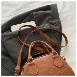 Detailed close-up of brown PU leather handbag texture with gold hardware on white fabric