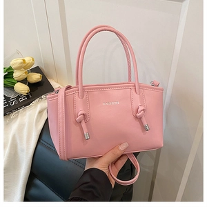 Gros plan d'un sac bandoulière rose avec poignée nouée argentée et texte FASHION