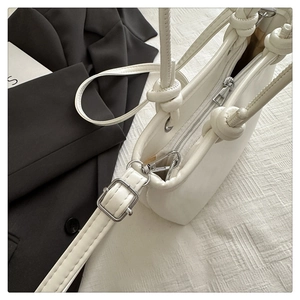 Detail der weißen Umhängetasche mit glattem Reißverschluss und Knotengriff-Design
