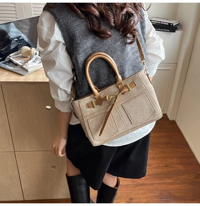 Detail of beige canvas handbag with brown leather straps and gold-tone metal hardware buckle