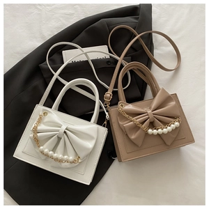 Détail de sacs à main élégants avec grand nœud et chaîne de perles en blanc et kaki