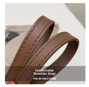 Close-up of brown leather shoulder strap with durable stitching and flexible texture