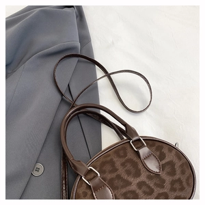 Detail of a brown leopard print oval handbag with faux suede texture and leather strap
