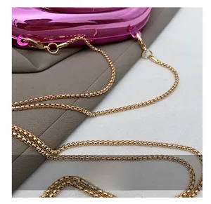 Détail du sac de soirée rose brillant avec une fine bandoulière chaîne carrée dorée