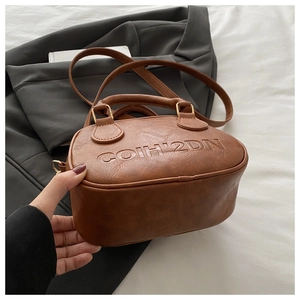 Detail of vintage brown PU leather bag featuring embossed COIH'2DN letters and gold hardware