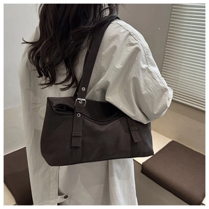 Détail du sac bandoulière marron foncé avec boucles argentées et cuir mat élégant
