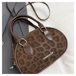 Top view of leopard print crossbody bowling bag on white fabric with grey blazer