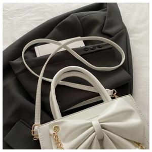 Détail du sac à main blanc avec grand nœud, chaînes dorées et accents de perles