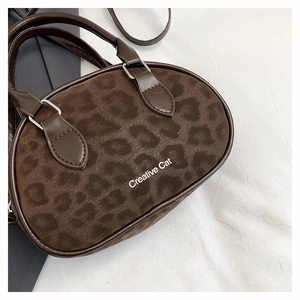 Detailed close-up of leopard print handbag with Creative Cat text and smooth leather handles