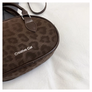Close-up of leopard print velvet handbag featuring Creative Cat text and leather trim