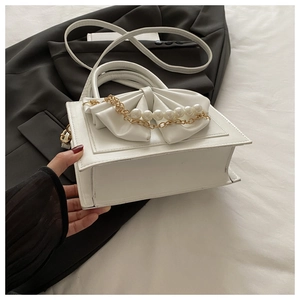 Détail du sac à main blanc avec grand nœud, perles et élégante chaîne dorée