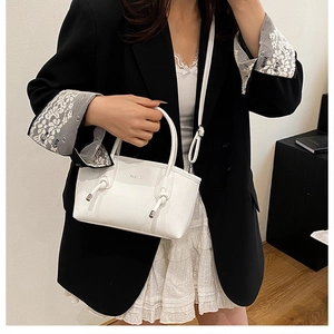 Détail du sac à main en cuir blanc crème avec texte FASHION et design décoratif à nœuds