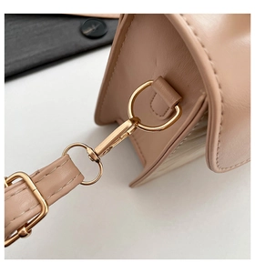 Detail of light beige crossbody bag with premium gold metal hook and leather texture